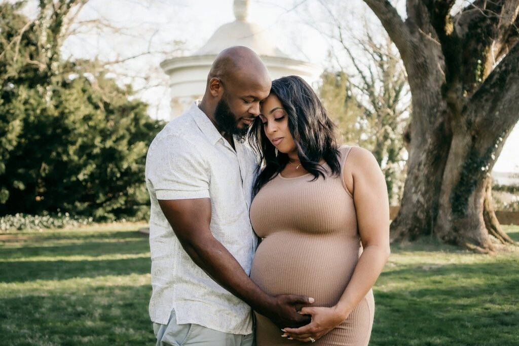 Casal em meio à natureza, onde a mulher está grávida representando o tema de quiropraxia para gestantes