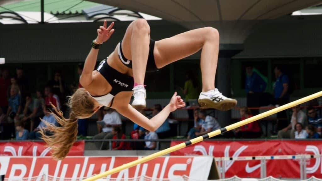 Atleta de alto rendimento, mulher, praticando salto em altura