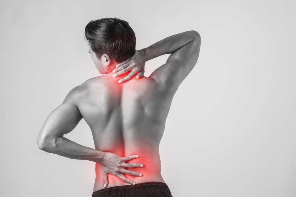 Homem levando as mãos às costas na região da cervical e da lombar que estão destacadas, representando dores causadas pela hérnia de disco